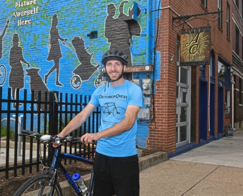 Jesse Descutner, assistant Main Street manager for the Northside Leadership Conference, stops on Foreland Street in Deutschtown near Allegheny City Brewery, on of 14 businesses participating in the We Like Bikes! initiative. (Nate Guidry/Post Gazette)